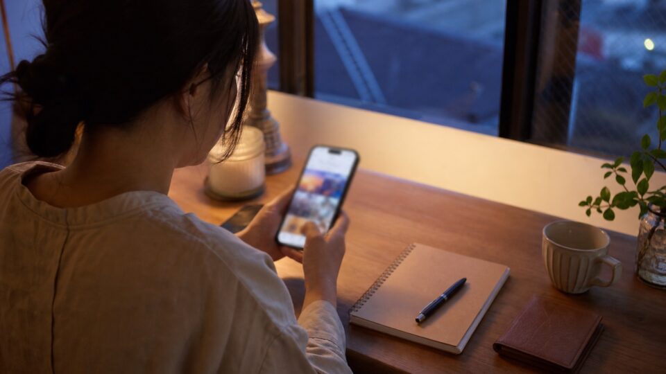 自宅でスマートフォンから公演の申込を確認する架空の成人ファン