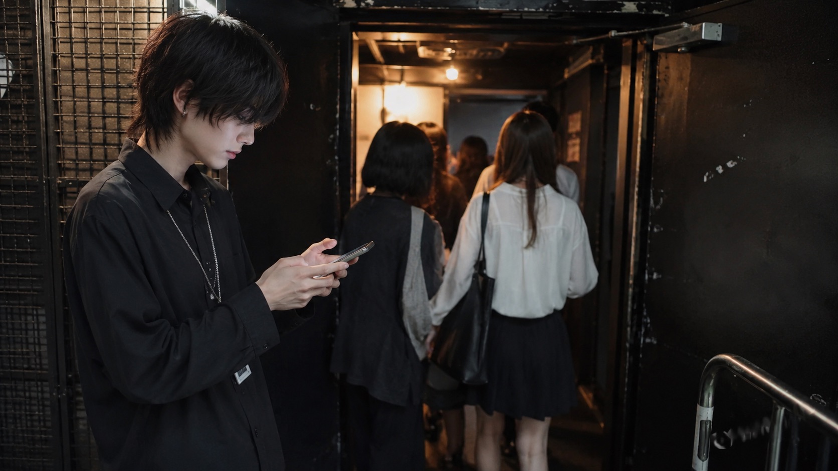 ライブ会場の入口付近でスマートフォンを確認する架空の成人男性
