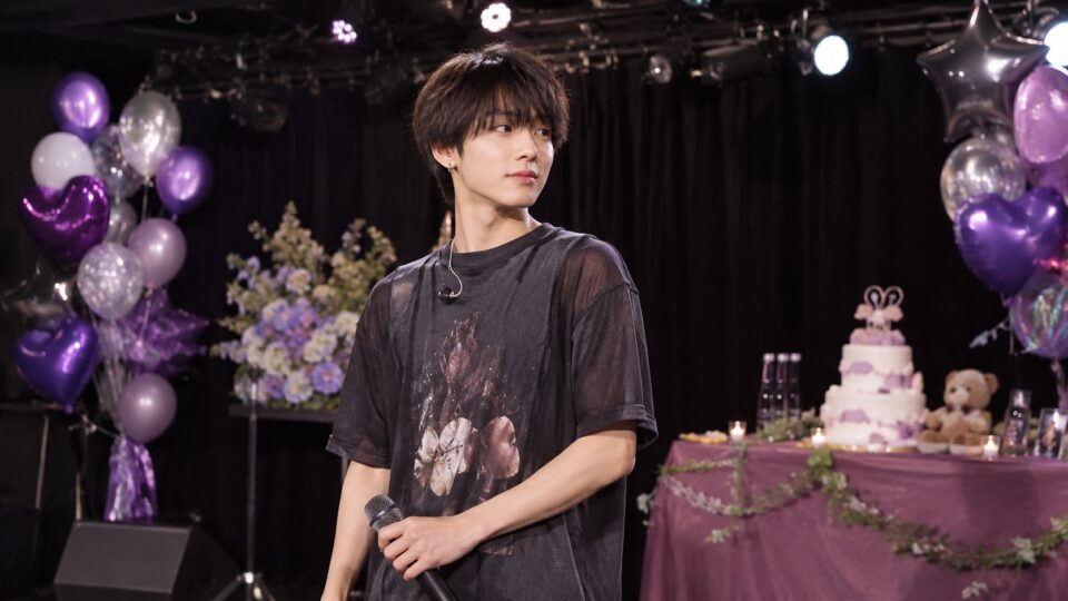 紫の風船で飾られたステージに立つ架空の成人男性アイドル