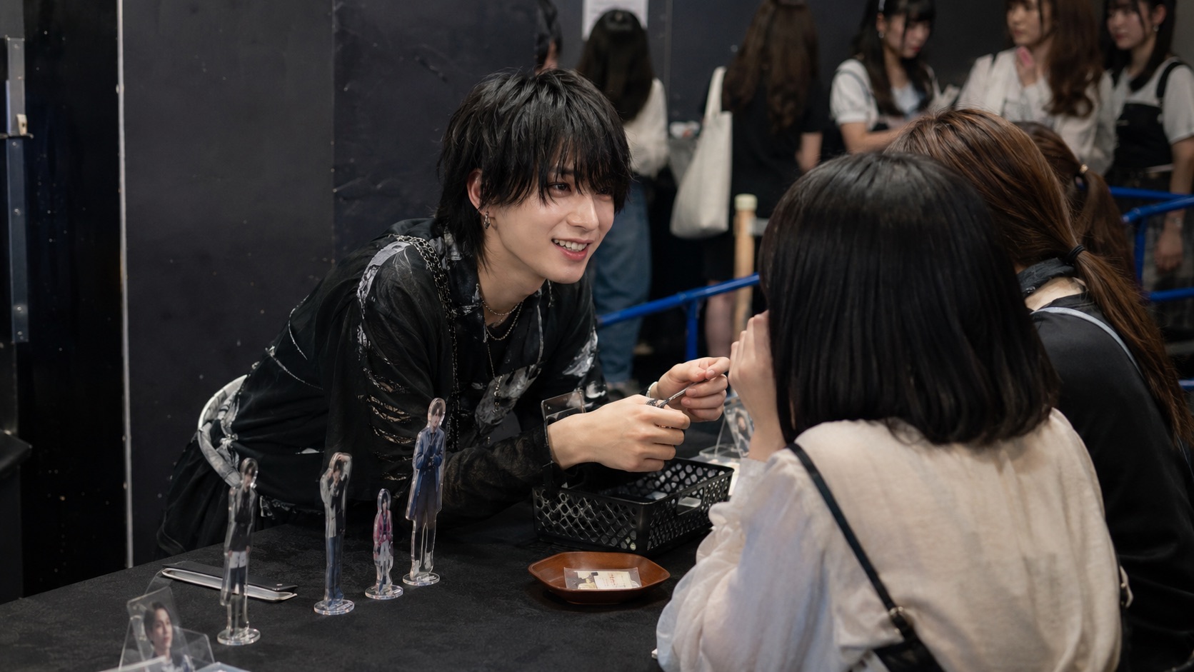 物販スペースで短い会話を交わす架空の成人アイドルとファン